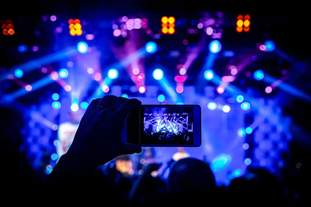 Fan recording a live concert inside a stadium supported by neutral-host DAS and shared multi-carrier wireless networks.